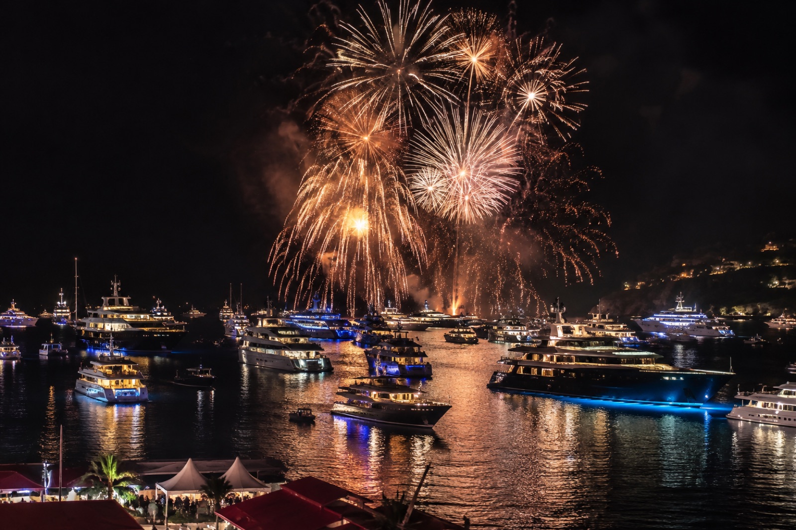 New Year's Eve fireworks over Gustavia harbor, dozens of lit superyachts on the water below