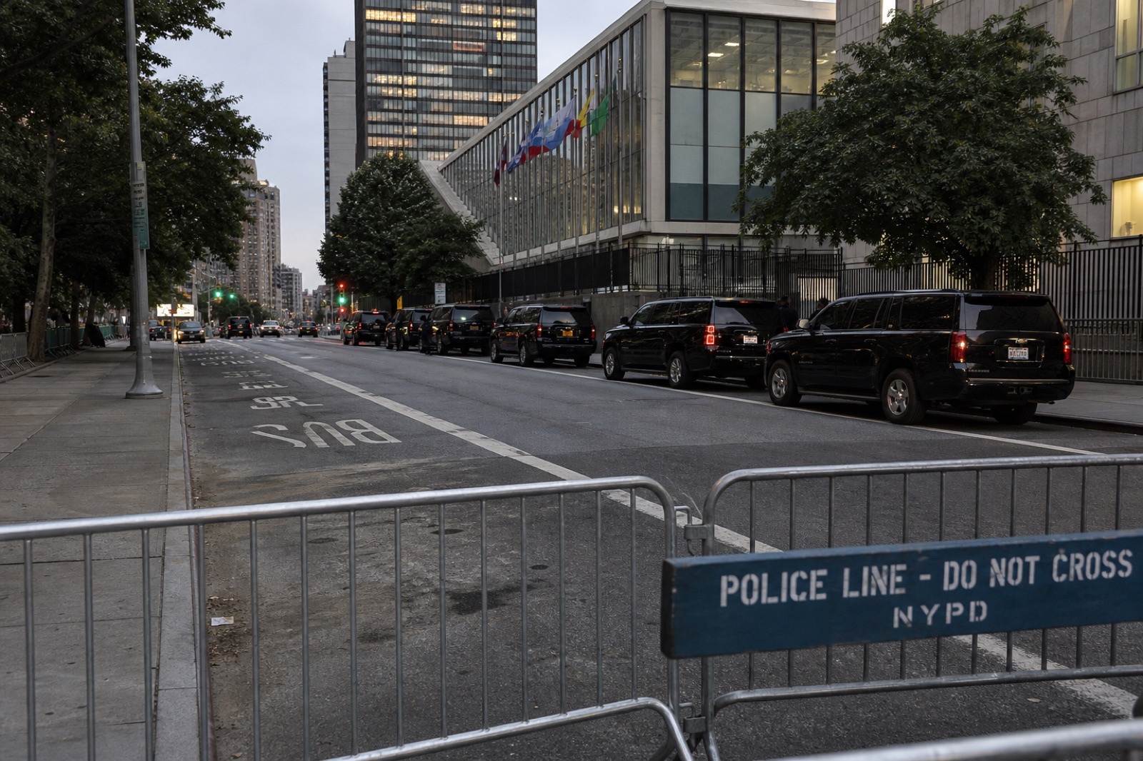 Black SUVs staged along a closed Manhattan avenue at dawn